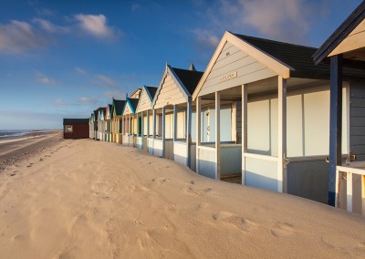 Strong winds & shifting sands in front of the beach huts at Southwold