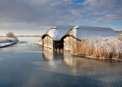 Thatched Boathouses on a frozen Hickling Broard, Norfolk Broads