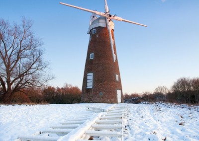 Billingford Windmill in Norfolk captured here in snow with the main sails on the ground undergoing restoration work.